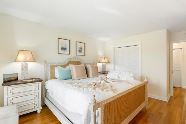 bedroom with light wood-type flooring, baseboards, and a closet