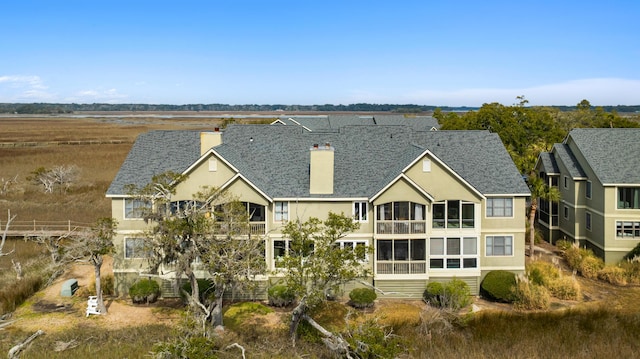 back of property featuring a shingled roof, a chimney, a residential view, and stucco siding