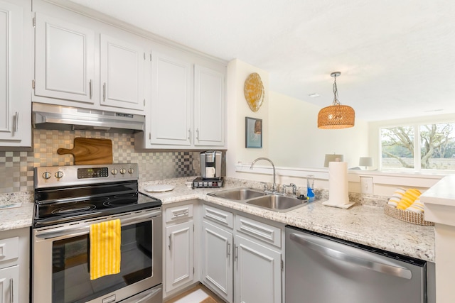 kitchen with under cabinet range hood, stainless steel appliances, a sink, hanging light fixtures, and tasteful backsplash