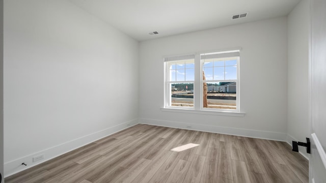 unfurnished room featuring light wood finished floors, baseboards, and visible vents