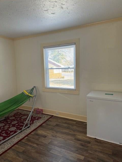 unfurnished bedroom featuring dark wood-type flooring, ornamental molding, white fridge, and a textured ceiling