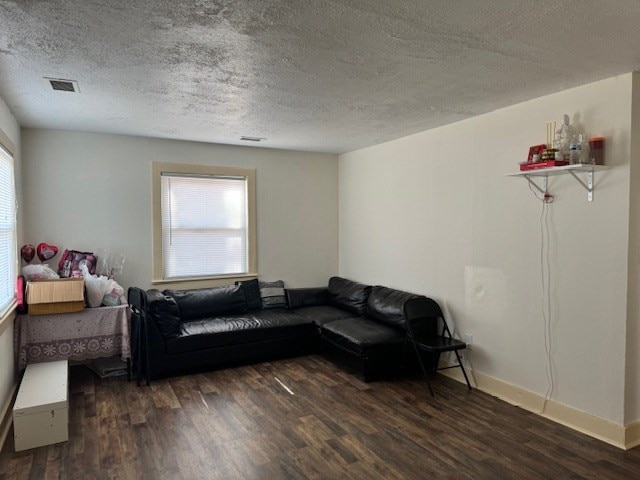 living room with a textured ceiling and dark hardwood / wood-style flooring