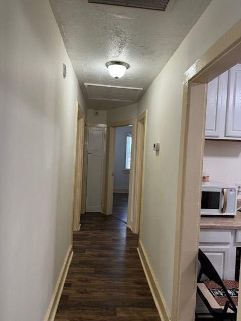 corridor featuring a textured ceiling and dark hardwood / wood-style floors