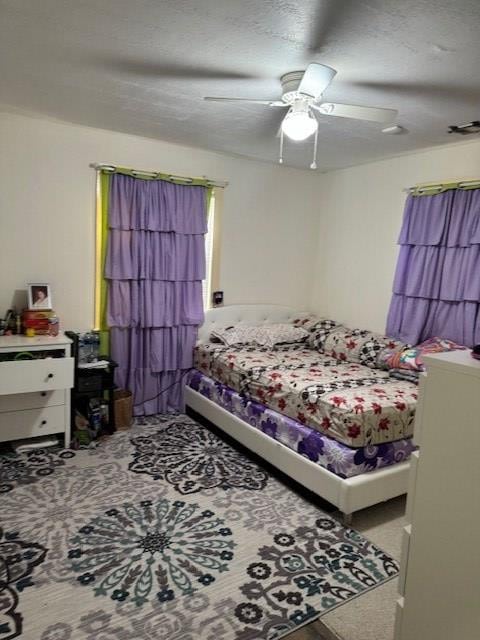 carpeted bedroom with a textured ceiling and ceiling fan