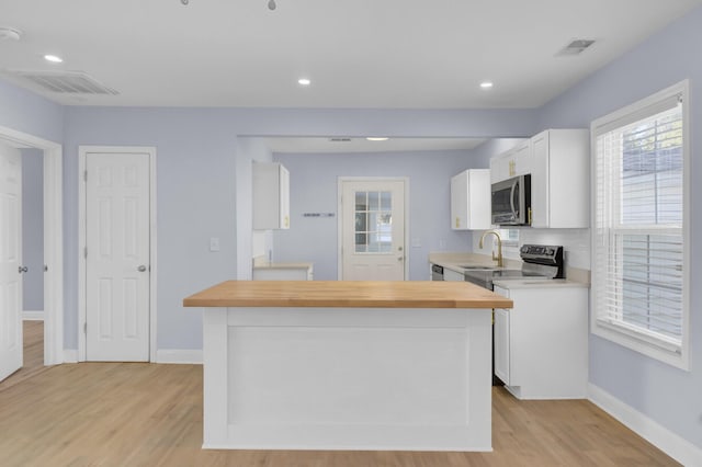 kitchen with white cabinetry, wood counters, sink, and light hardwood / wood-style floors