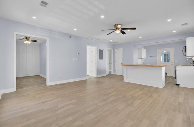 unfurnished living room featuring light hardwood / wood-style flooring, electric panel, and ceiling fan