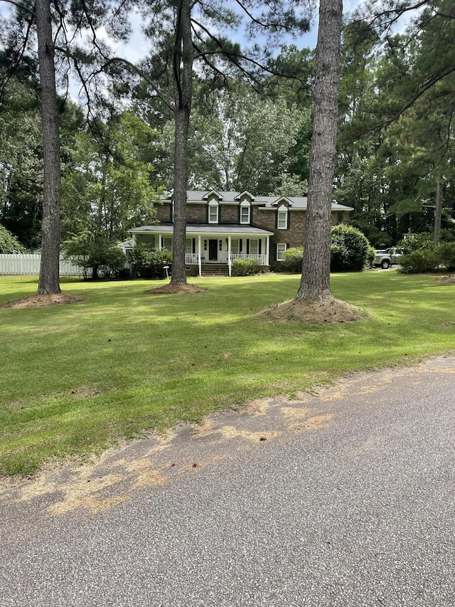 view of front of home with a front lawn, a porch, and fence