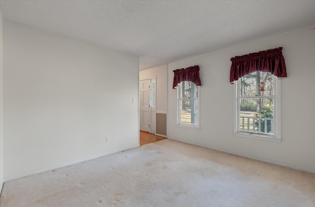 carpeted spare room featuring a textured ceiling and baseboards