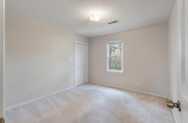 carpeted spare room featuring visible vents, a textured ceiling, and baseboards