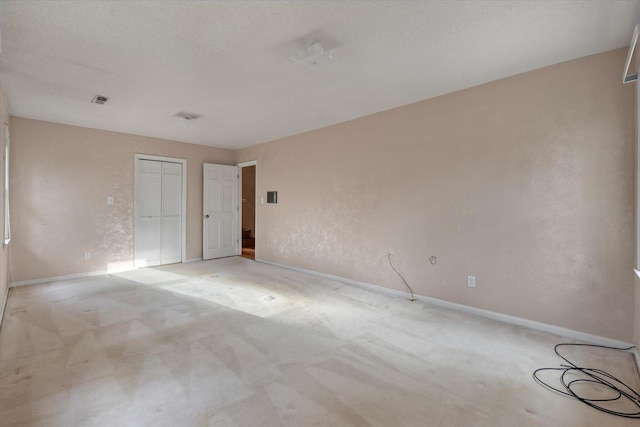 unfurnished bedroom with light carpet, baseboards, a closet, and a textured ceiling