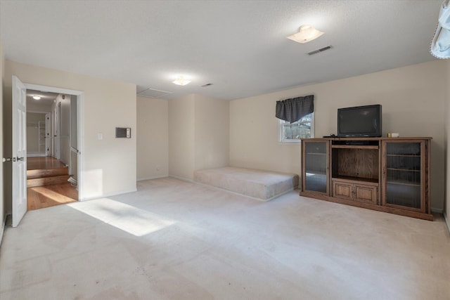 interior space featuring visible vents, a textured ceiling, baseboards, and carpet floors