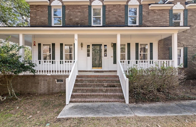 entrance to property featuring brick siding and covered porch