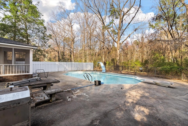 view of swimming pool with fence, a water slide, a diving board, a fenced in pool, and a patio area