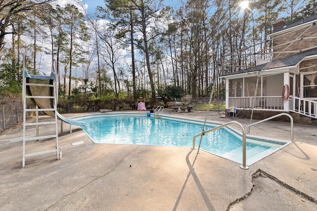 outdoor pool with a sunroom, fence, a water slide, and a patio area