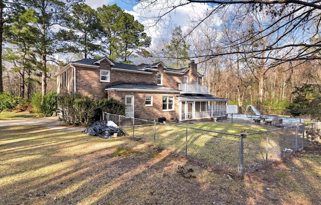 rear view of house featuring a balcony, a yard, a fenced backyard, an outdoor pool, and brick siding