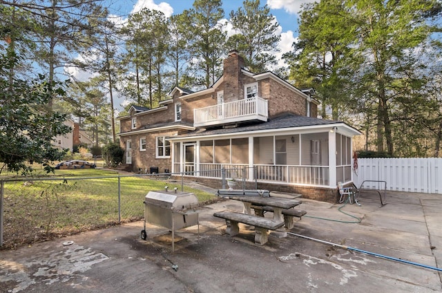 back of house featuring a balcony, a patio area, a sunroom, and a chimney