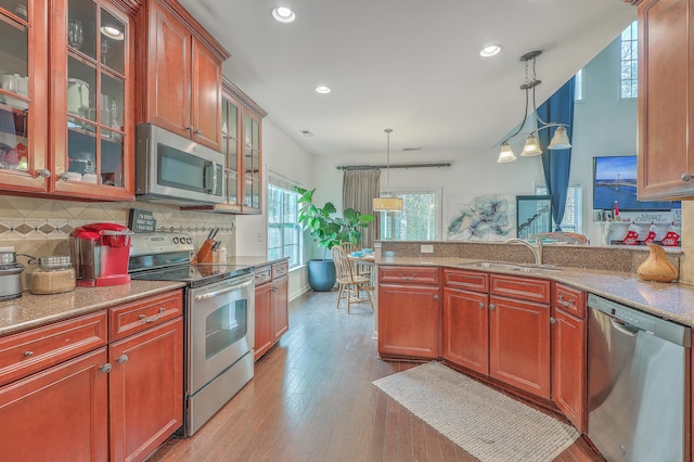 kitchen featuring a sink, decorative backsplash, appliances with stainless steel finishes, and pendant lighting