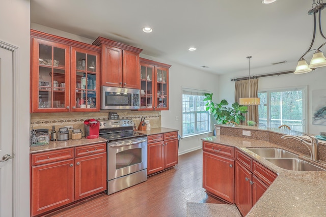 kitchen with a wealth of natural light, decorative backsplash, appliances with stainless steel finishes, and a sink