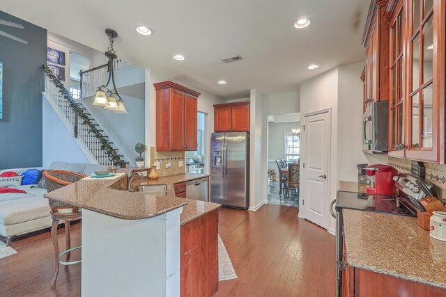 kitchen featuring visible vents, dark wood-type flooring, appliances with stainless steel finishes, a peninsula, and a sink