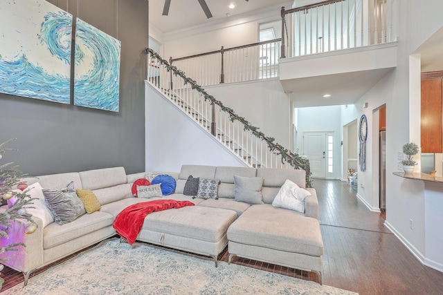 living room featuring baseboards, stairway, ornamental molding, hardwood / wood-style floors, and a high ceiling