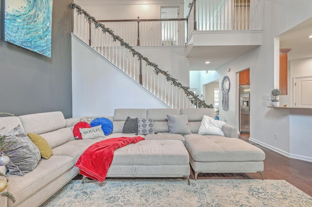 living area with stairs, a high ceiling, wood finished floors, and baseboards