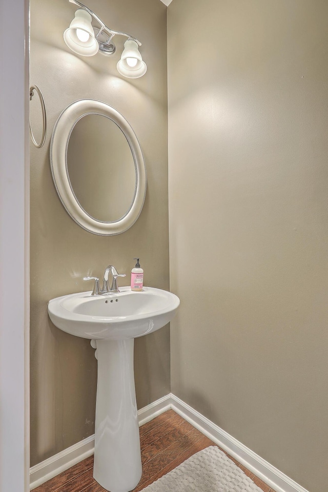 bathroom with a sink, baseboards, and wood finished floors