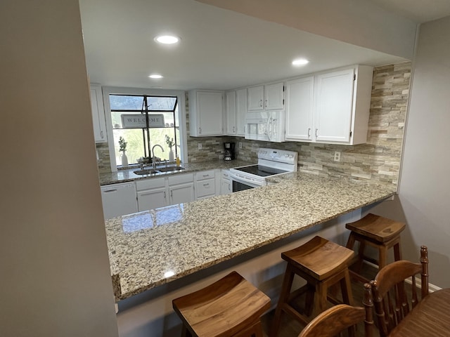 kitchen featuring a breakfast bar, white appliances, backsplash, sink, and white cabinetry