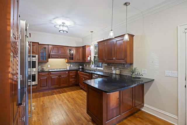 kitchen with pendant lighting, decorative backsplash, light wood-type flooring, appliances with stainless steel finishes, and kitchen peninsula