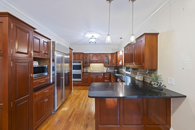 kitchen featuring kitchen peninsula, appliances with stainless steel finishes, backsplash, sink, and pendant lighting