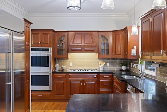 kitchen with pendant lighting, custom exhaust hood, sink, decorative backsplash, and stainless steel appliances