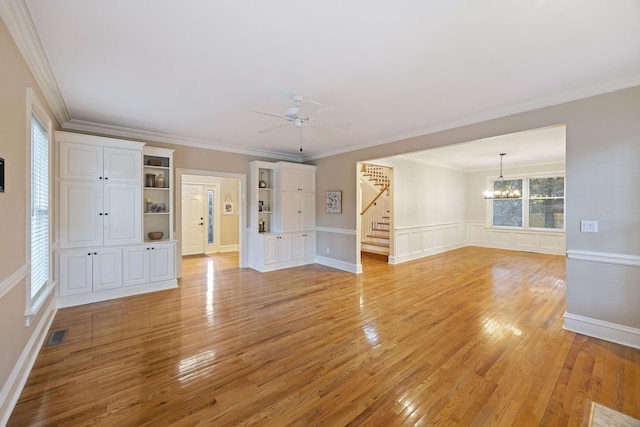 unfurnished living room with light wood-type flooring, ceiling fan with notable chandelier, and crown molding