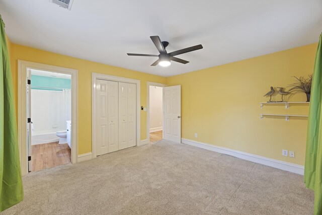 unfurnished bedroom featuring ensuite bathroom, a closet, ceiling fan, and light colored carpet