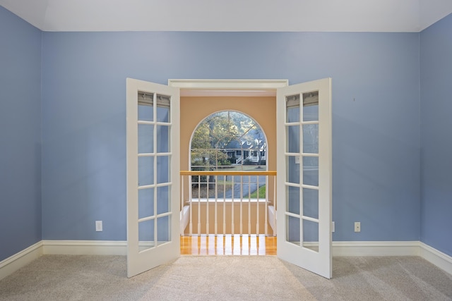 carpeted spare room featuring french doors