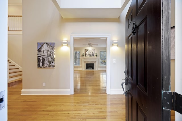 entryway with ceiling fan, light hardwood / wood-style floors, and a fireplace