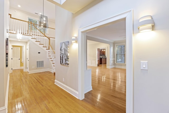 hall featuring crown molding, a healthy amount of sunlight, and light wood-type flooring