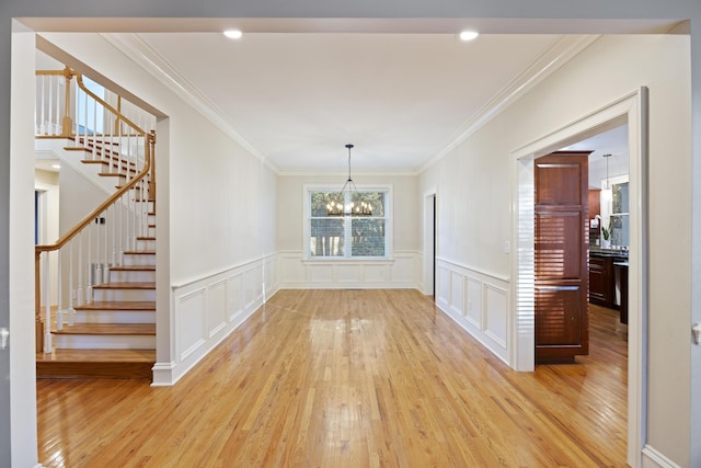 unfurnished dining area with light wood-type flooring, crown molding, and an inviting chandelier