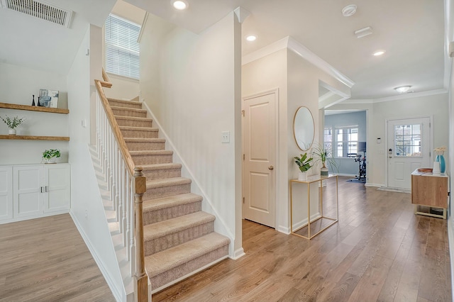 stairs featuring visible vents, baseboards, ornamental molding, recessed lighting, and wood finished floors