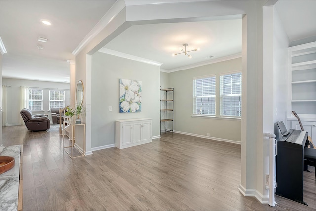 interior space featuring visible vents, wood finished floors, baseboards, and ornamental molding