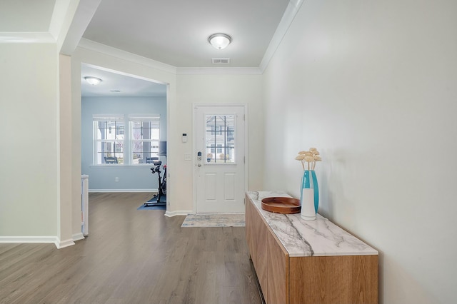 foyer with visible vents, baseboards, wood finished floors, and crown molding