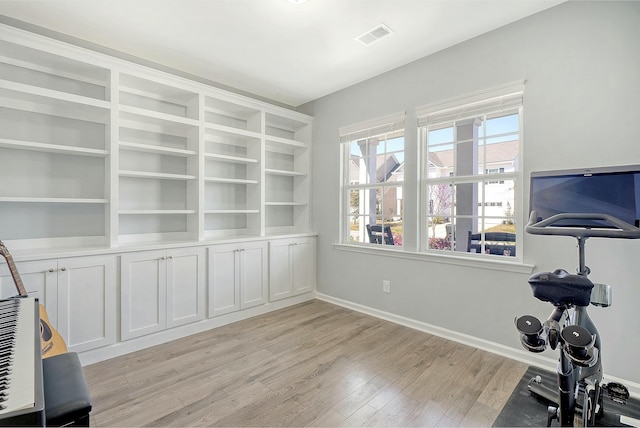 exercise area featuring light wood-style floors, visible vents, and baseboards