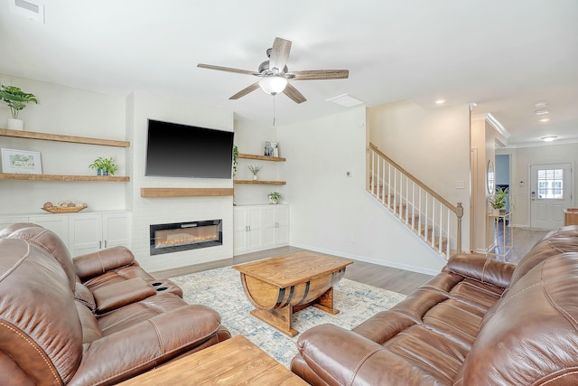 living area with wood finished floors, baseboards, visible vents, stairs, and a large fireplace