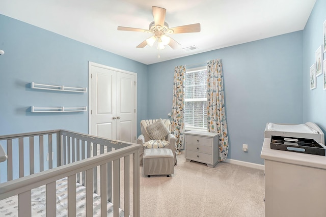 bedroom featuring visible vents, a crib, baseboards, carpet flooring, and a closet