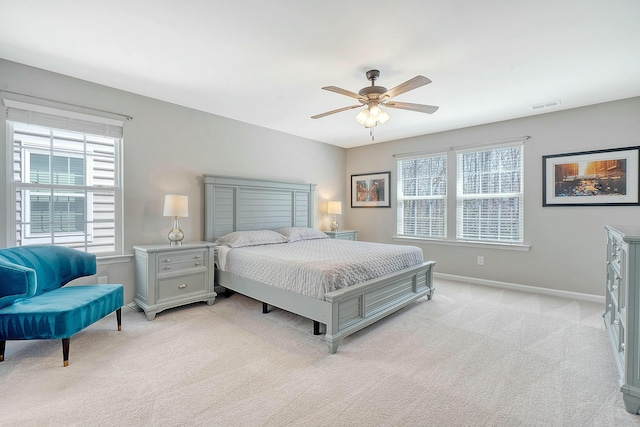 bedroom featuring multiple windows, baseboards, visible vents, and light carpet