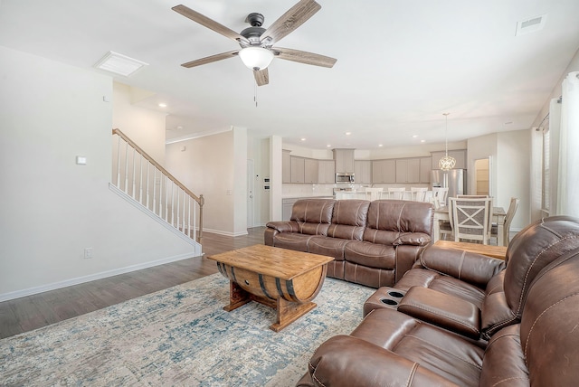 living room featuring stairs, baseboards, visible vents, and light wood finished floors