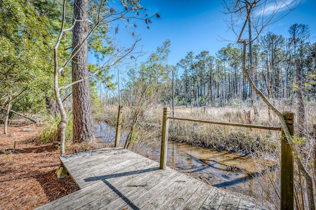 wooden deck with a forest view and a water view