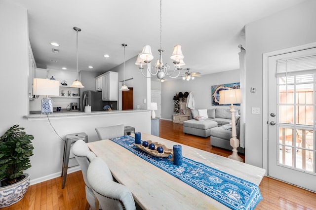 dining area featuring light wood-type flooring, ceiling fan with notable chandelier, baseboards, and recessed lighting