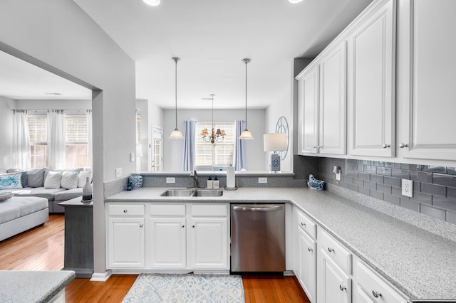 kitchen with open floor plan, stainless steel dishwasher, and white cabinets