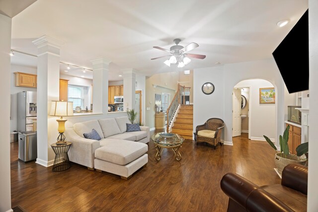 living room featuring dark wood-type flooring, decorative columns, and ceiling fan