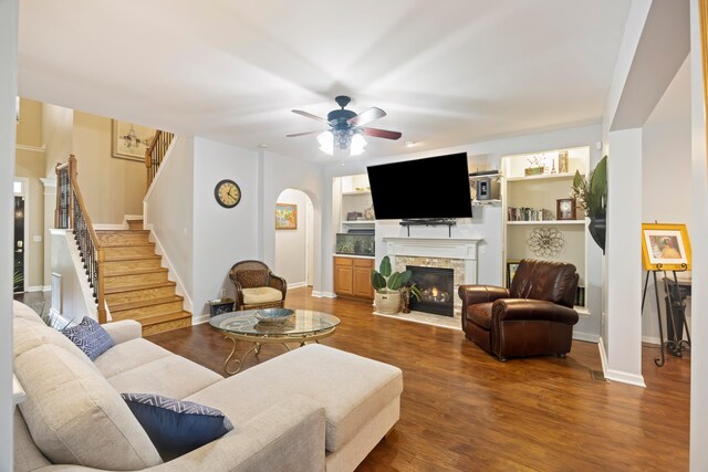 living room featuring ceiling fan, hardwood / wood-style flooring, a fireplace, and built in shelves