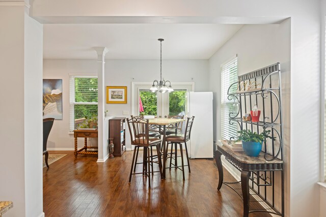 dining area featuring dark hardwood / wood-style floors, a chandelier, and decorative columns